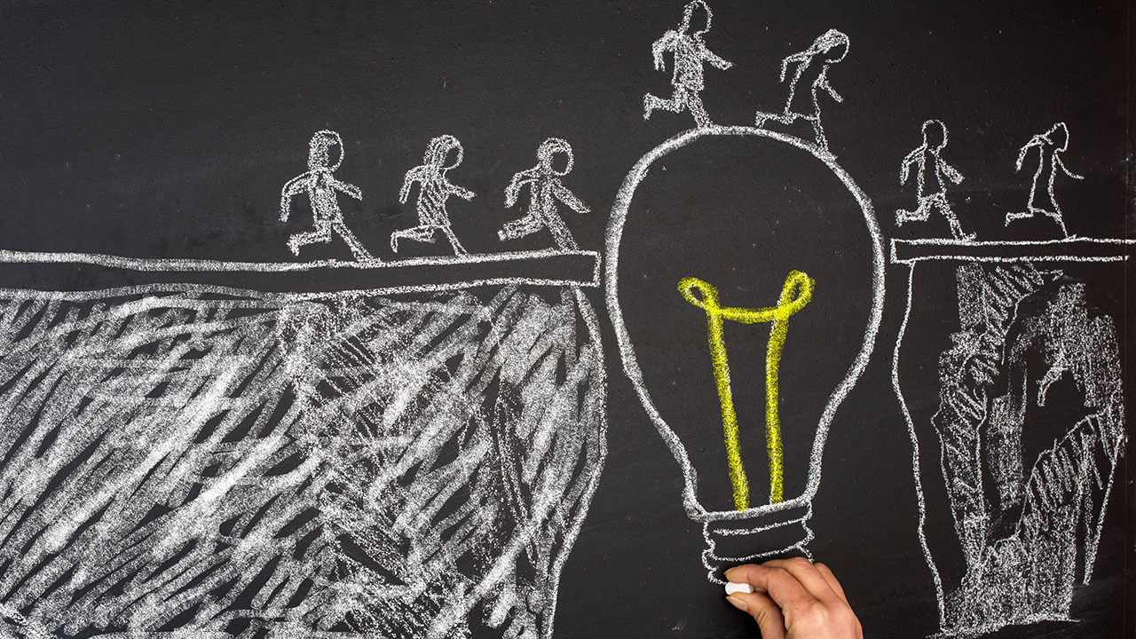 Abstract chalk drawing of people walking over a lightbulb Abstract chalk drawing of people walking over a lightbulb