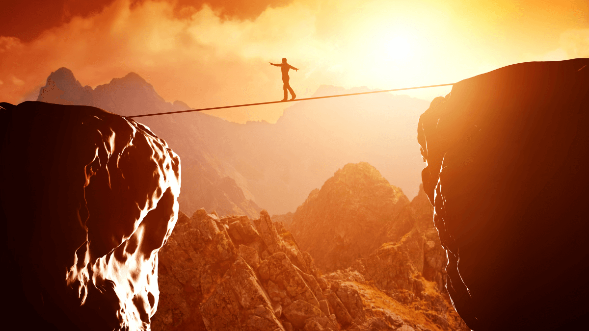 Person walking in tightrope between valley Person walking in tightrope between valley